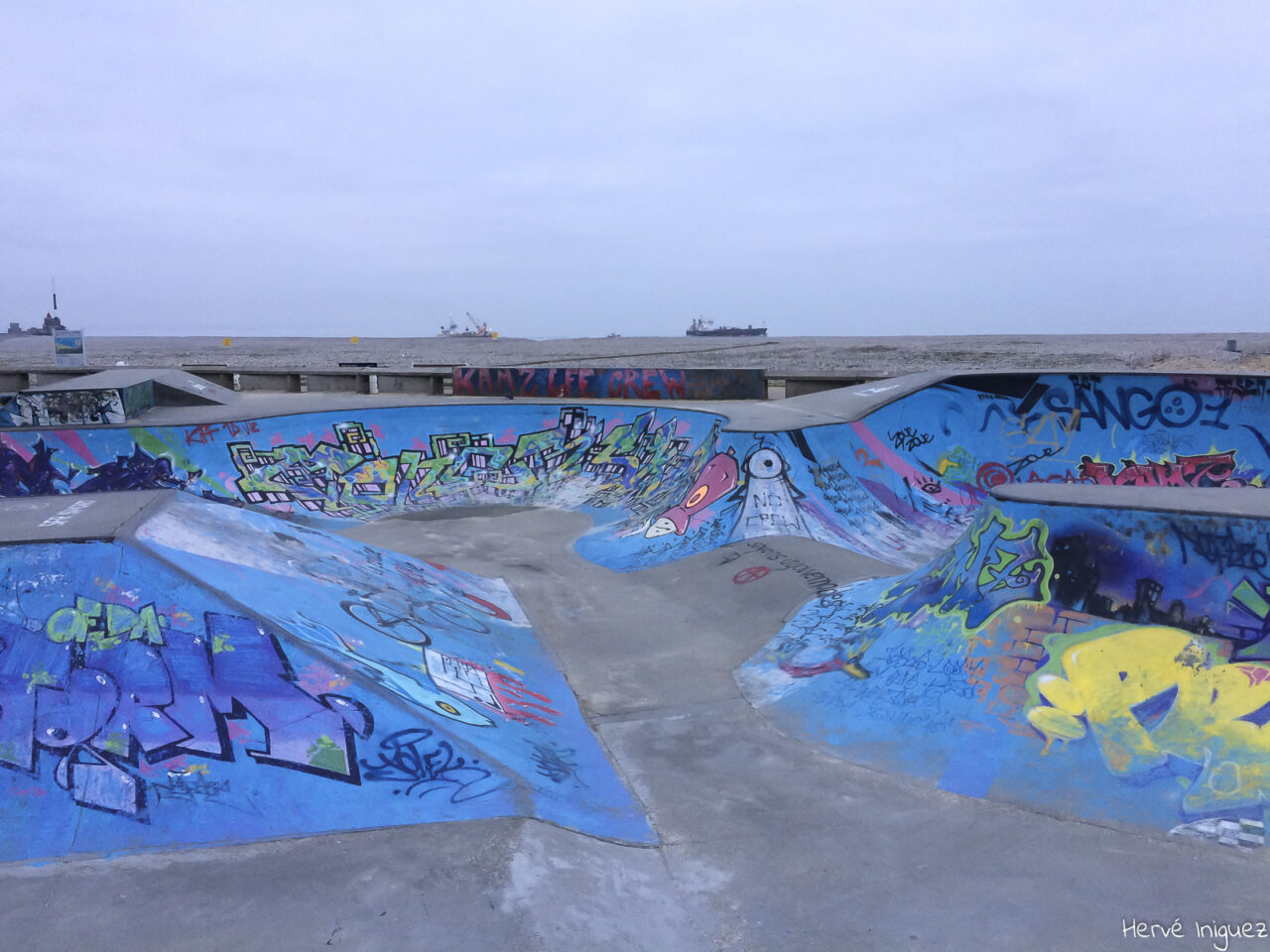 Photographie d'une piste de Skateboard sur le port du Havre. La piste est entièrement décorée par des tags très colorés.